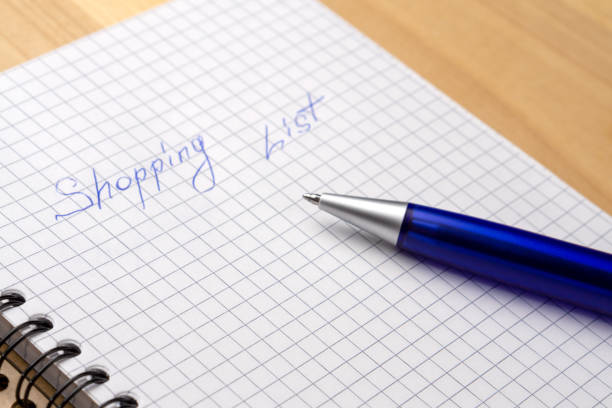 istock Blue pen on a notebook with sheets in a cage. Sign Shopping List. Close-up 1165161593