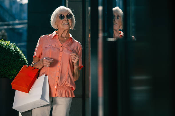 istock Joyful aged woman looking happy while going shopping 1165163560