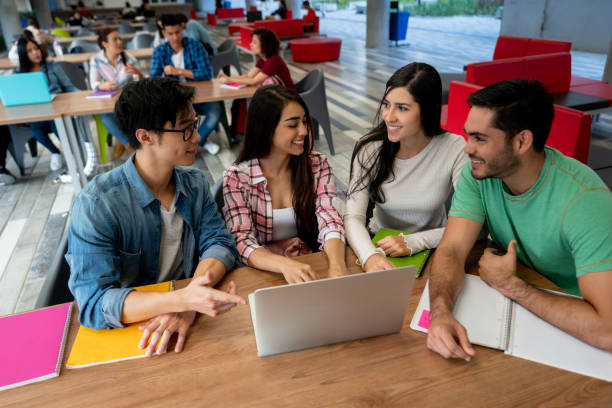 istock Group of college friends with a tutor studying together using a laptop and notebooks 1165164467