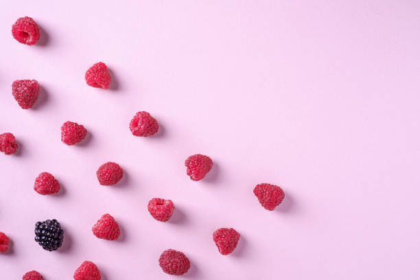 istock Raspberry sweet organic juicy berries with single blackberry, pattern, texture, on pink paper background, flat lay 1165168142