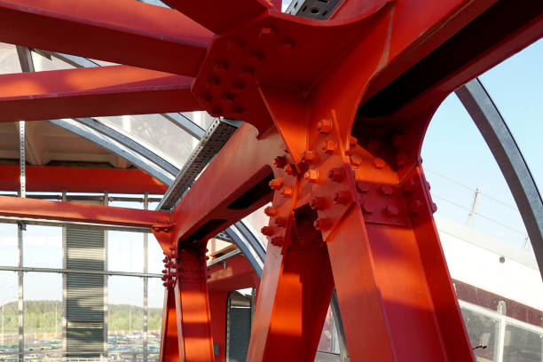 istock Red iron beams bolted on. Angular connection of several iron beams in one place close up. Crossing the road, hinged bridge. 1165170517