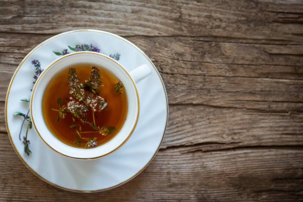 Cup of tea with thyme on wooden background with copy space