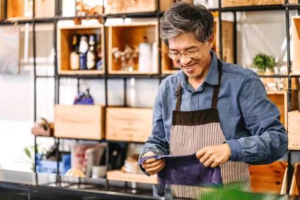 istock Asian senior barista working behind bar counter 1165184188
