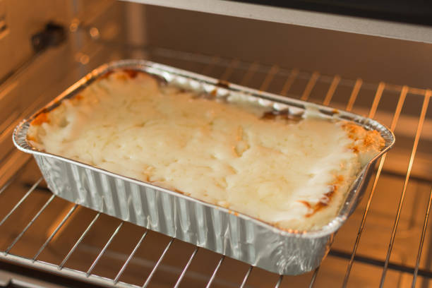 istock Cheese lasagna in a baking tray in the oven close-up. 1165185826