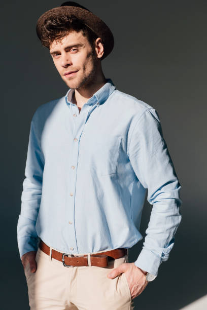istock handsome man in blue shirt and brown hat standing in sunlight 1165185865