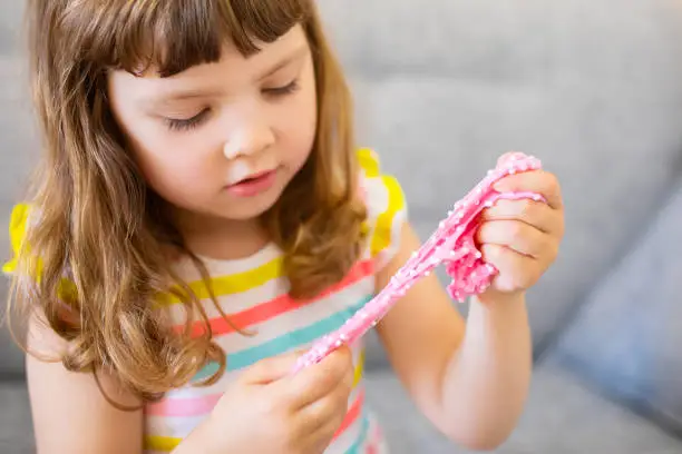 Photo of Little girl holding pink slime