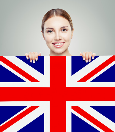 Portrait of happy pretty girl with UK flag background. Young woman learning english language and traveling in United Kingdom