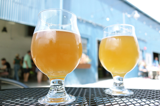Two craft beer pints at a microbrewery in an outdoor courtyard table