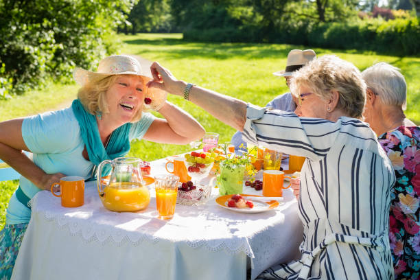 istock Elderly friends having picnic in sunny lush nature. 1165188632