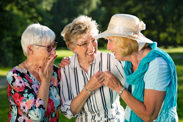 Family members gossiping. Three elderly women standing in the park, sharing secrets.