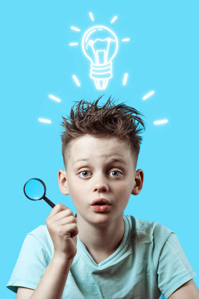 istock a boy in a light t-shirt holding a small magnifying glass on blue background 1165189235