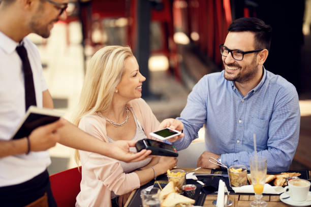 istock Happy man making smart phone payment while being with girlfriend in a bar. 1165189526
