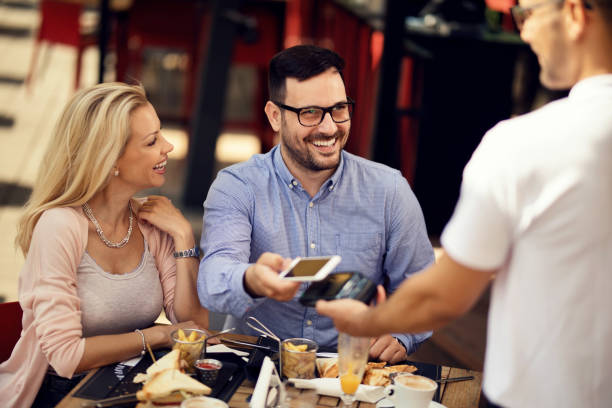 istock Happy couple making wireless payment with smart phone in a restaurant. 1165189643