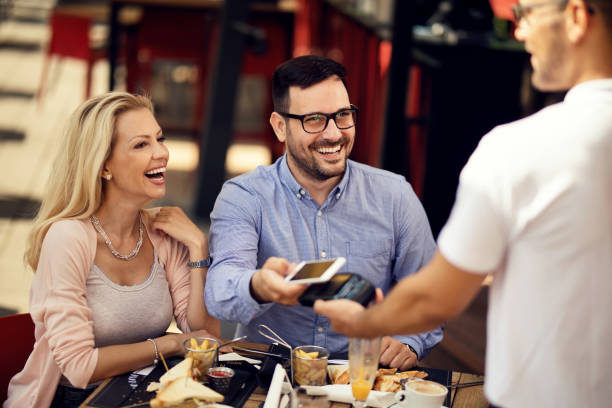 istock Cheerful guests paying with mobile phone while having lunch in a restaurant. 1165189650