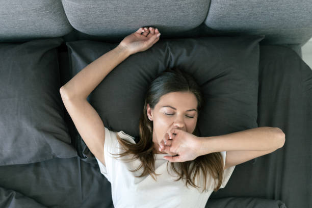 jeune femme adulte dormant sur le lit le matin - pillow wake up yawning sleeping photos et images de collection