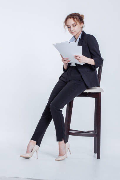 istock Young office worker girl in classic suit keeps clean sheets of paper isolated on white background. Cute financier lean on chair, holding clipboard in hands, thumbnail month's report in workplace. 1165190889