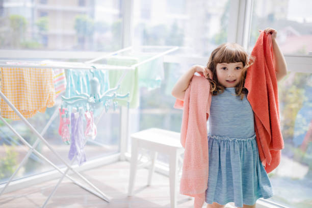 istock Child in laundry room. Clean washed clothes on drying rack. Mother's little helper 1165190984