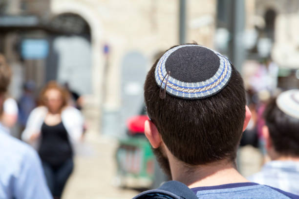 Jewish man walking in the ancient streets of the old city of Jerusalem Jerusalem, Israel - June 14, 2018: Jewish man walking in the ancient streets of the old city of Jerusalem wearing a kippah or yarmulke, a traditional Jewish headwear. yarmulke photos stock pictures, royalty-free photos & images