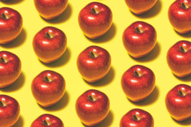 istock Red apple repetitive flat lay on yellow background 1165195477
