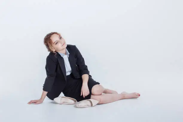 Woman in alcohol intoxication after corporate party. Girl wearing unbuttoned business jacket and takes off shoes from fatigue. Isolated white background