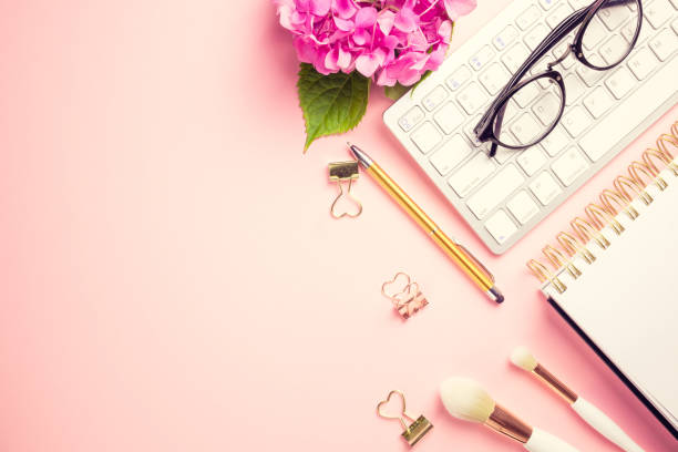 istock Female workspace with laptop, pink hydrangea, golden accessories, pink diary on pink background. 1165201312