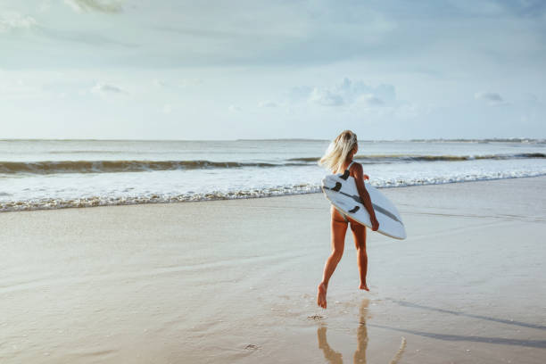 istock Surfer girl walking with board on the sandy beach. 1165204238