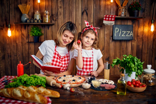 istock Mother teaching daughter cooking pizza and smiling 1165206281