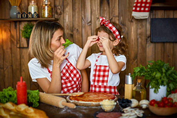 istock Mother and daughter cooking pizza and have fun 1165206398