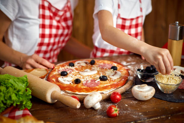 istock Mother teaching daughter cooking pizza and smiling 1165206508