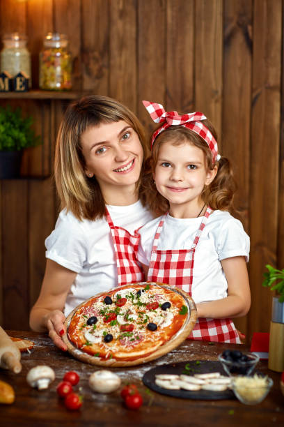 istock Happy Smiling mother and daughter with cooked pizza 1165206719
