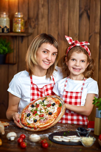 istock Happy Smiling mother and daughter with cooked pizza 1165206723