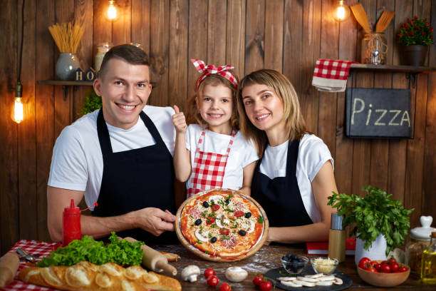 istock Happy family in aprons smiling and holding cooked pizza 1165206726