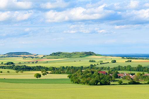 This photo was taken in France, in Burgundy, in the Nièvre, near Varzy. We see the French countryside grown with wheat, rapeseed and barley. In the foreground, we see a typical French village and in the background, we can see limestone cliffs.