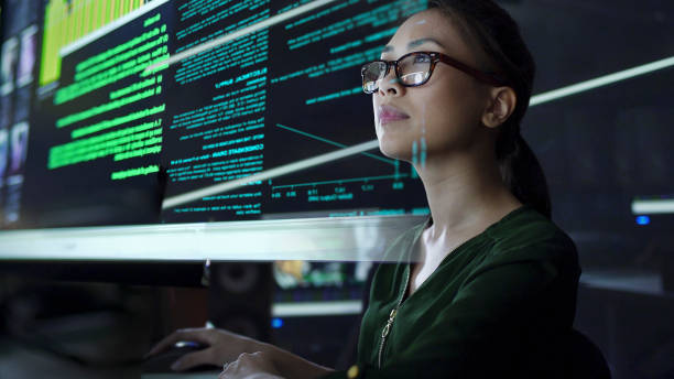 Large see through screen Stock photo of a young Asian woman looking at see through data whilst seated in a dark office defending activity photos stock pictures, royalty-free photos & images