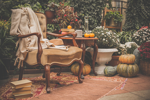Table with wine, books and coffee and chair in autumn garden.