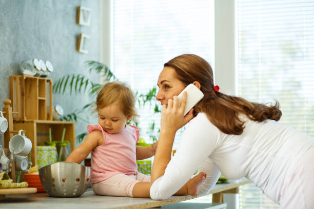 istock Mother talking on the phone while her baby daughter is playing 1165214376
