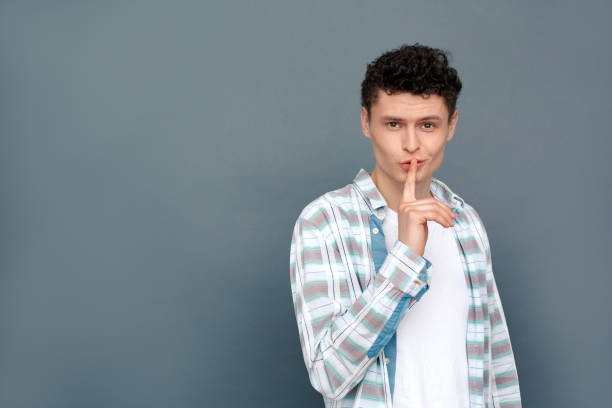 istock Man isolated on gray wall free style standing looking camera showing silence gesture 1165215112