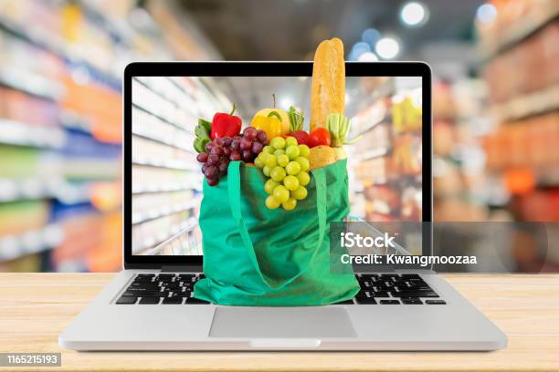 Supermarkt Gang Verschwommenen Hintergrund Mit Laptopcomputer Und Grüne Einkaufstasche Auf Holz Tisch Lebensmittel Onlinekonzept Stockfoto und mehr Bilder von Internet