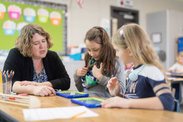 istock First grade teacher helping out students at their desks 1165215319