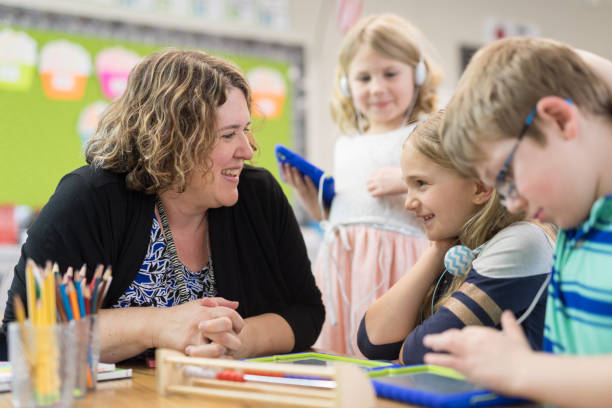 istock First grade teacher helping out students at their desks 1165215320