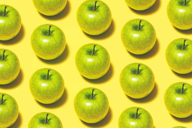 istock Green apple repetitive flat lay on yellow background 1165215556
