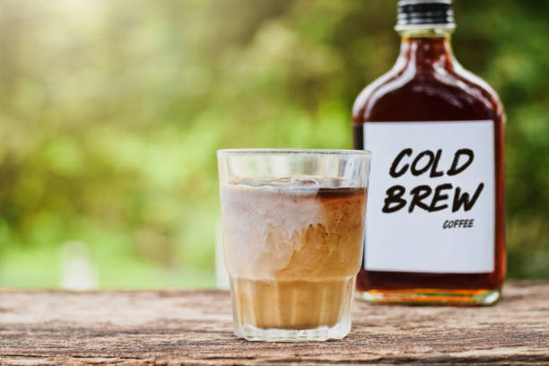 A glass of cold brew coffee with milk on a table outside with cold-brew coffee in a glass bottle for take away