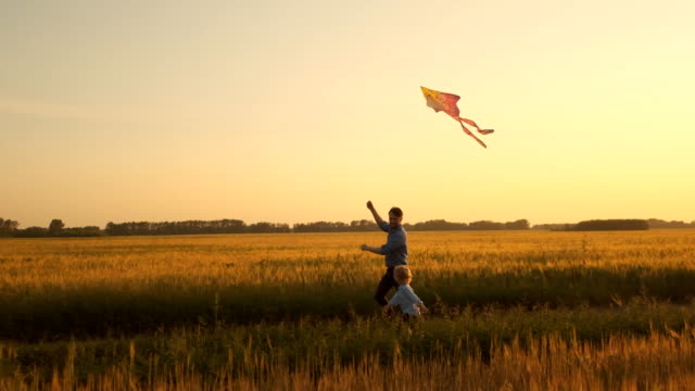 Father and son playing with a kite in nature at sunset. Unity of family and outdoor recreation. Happy family. Slow motion