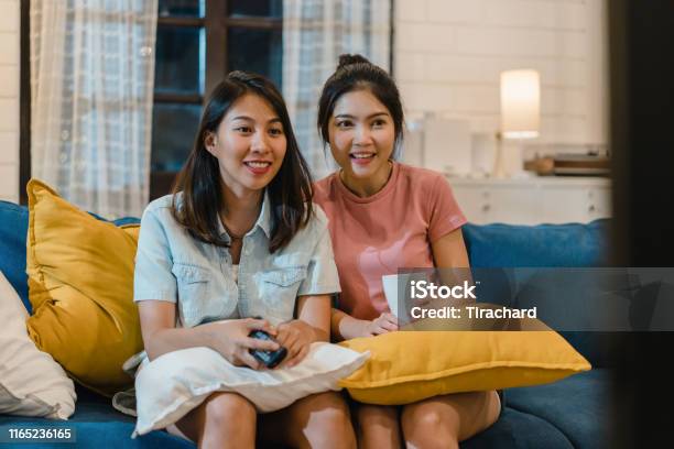 Lesbian Lgbt Women Couple Watching Television At Home Asian Female Lover Feeling Happy Funny Moment Looking Drama Entertainment Together On Sofa In Living Room In Night Concept Stock Photo - Download Image Now