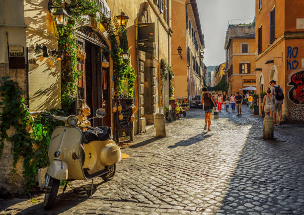 menschen und gebäude in einer gasse von trastevere, rom, italien - vespa rom stock-fotos und bilder