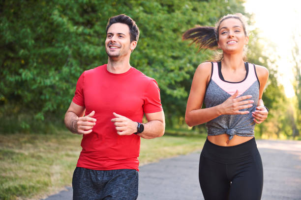 istock Smiling young couple running in the park 1165244471