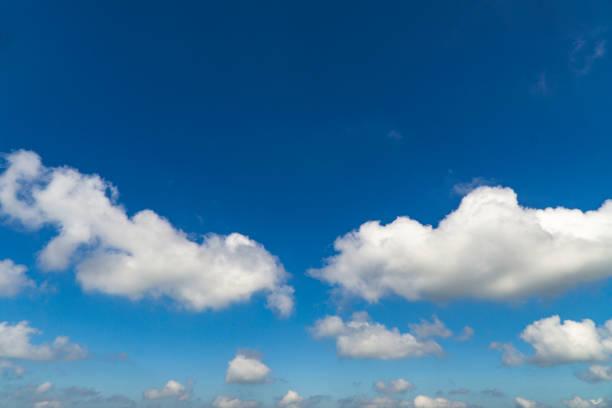 istock White fluffy clouds over a deep blue sky beautiful summer air background 1165249408
