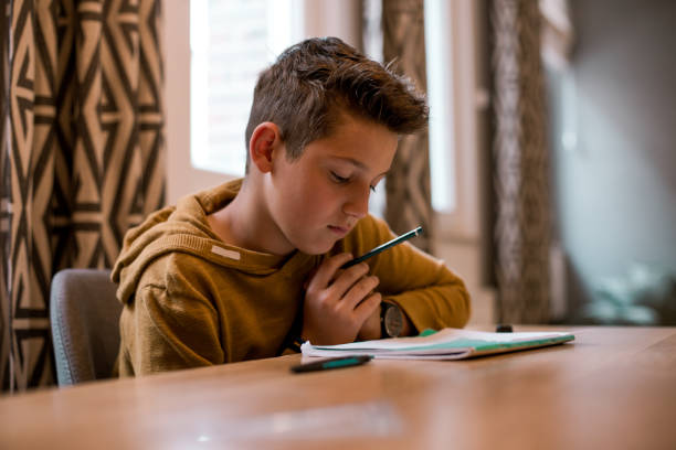 istock Teenage boy sitting at the table doing his school homework. 1165250400