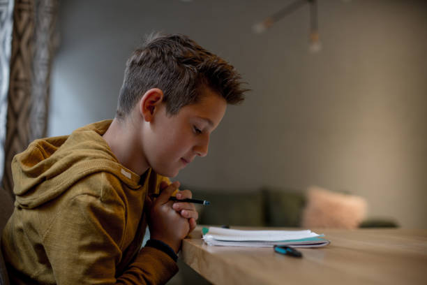 istock Teenage boy sitting at the table doing his school homework. 1165250445