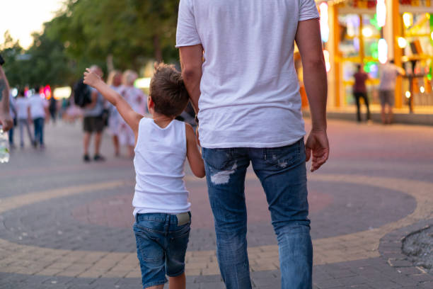 istock back view father and son walking together through city park in summer 1165251346